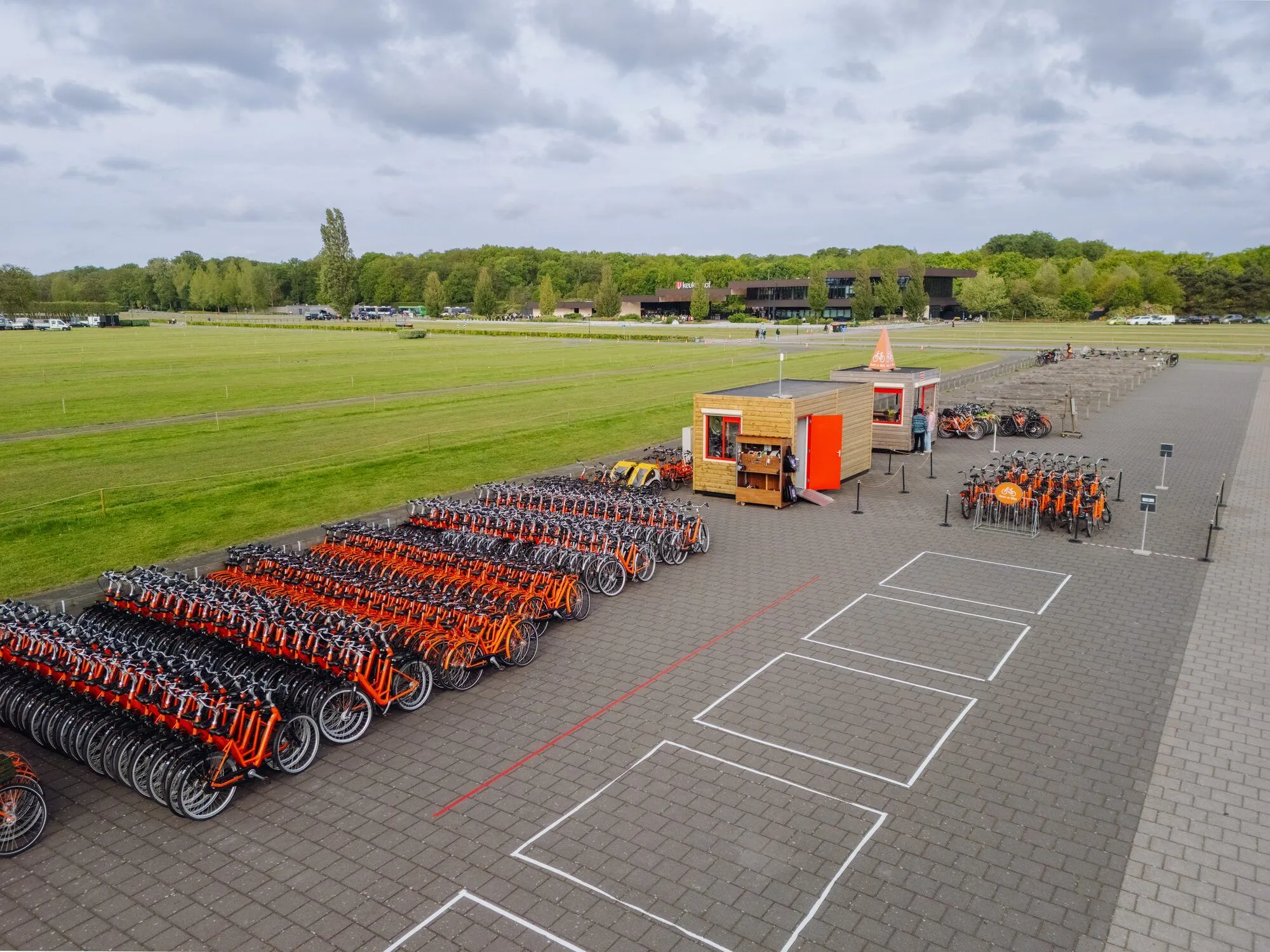 Een rij oranje deelfietsen klaar voor verhuur op een evenement
