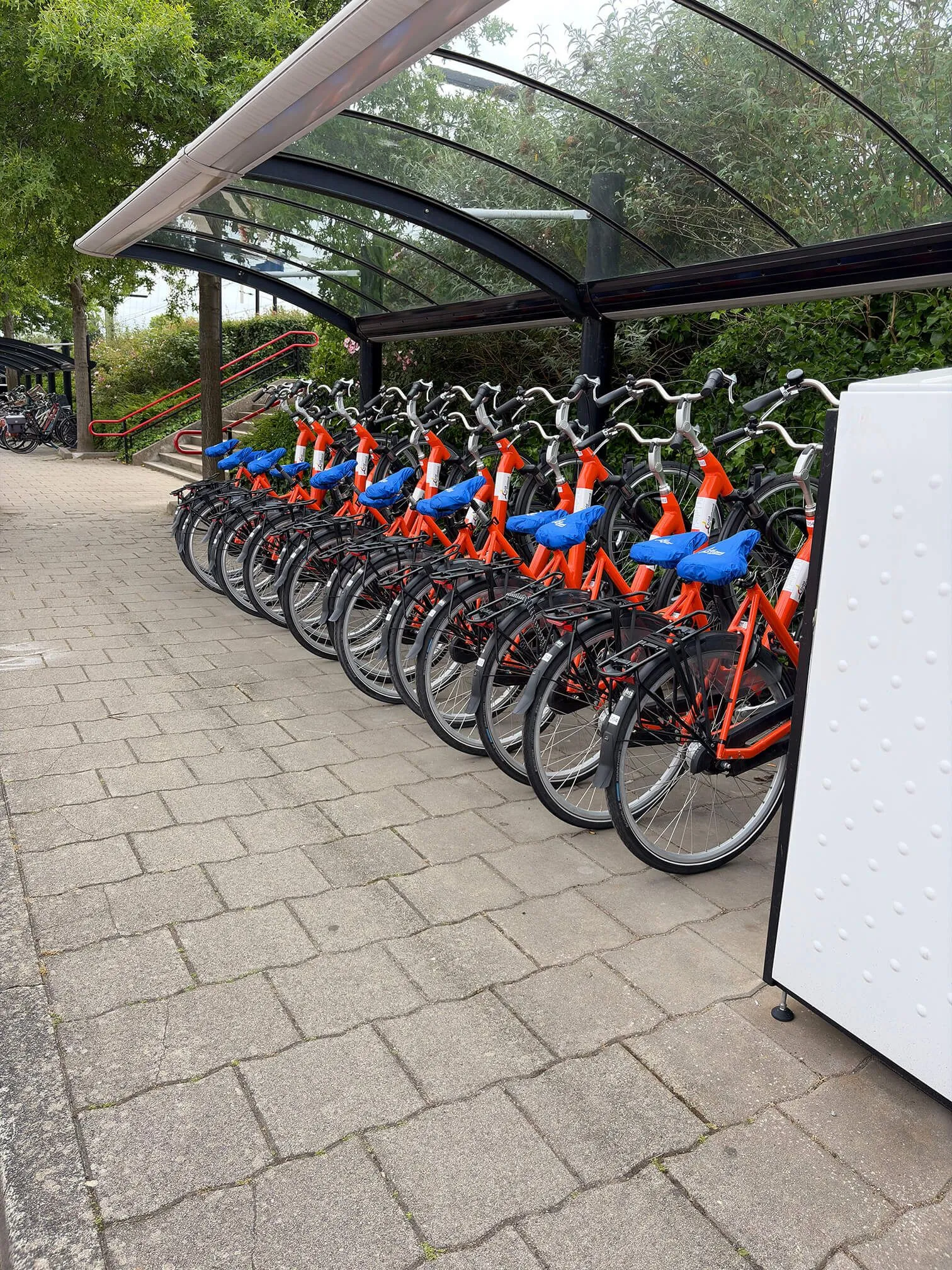 Twee mensen fietsen op elektrische deelfietsen langs een Hollandse molen